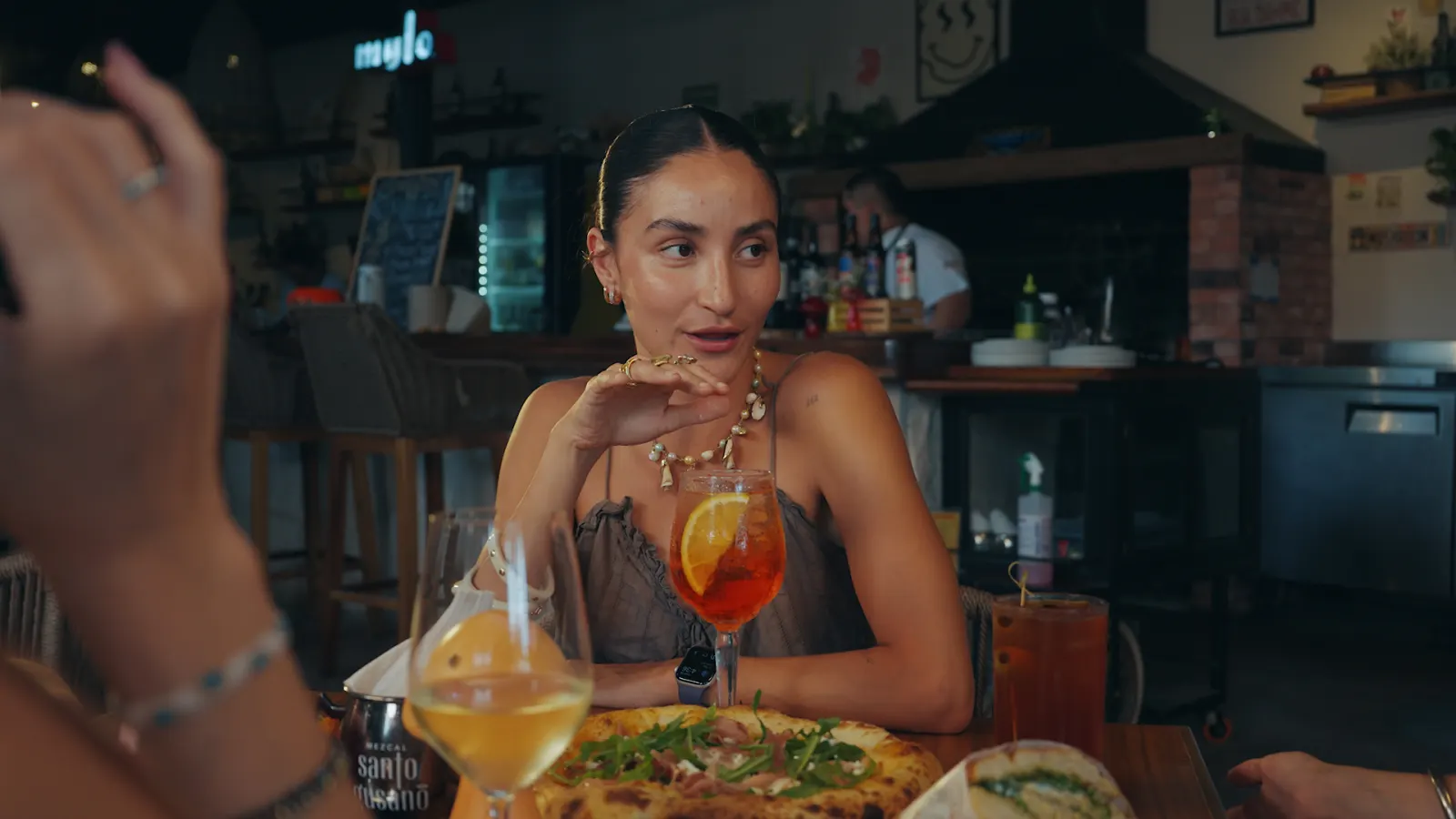 Comensal en la barra de Mylo con pizza y Aperol spritz